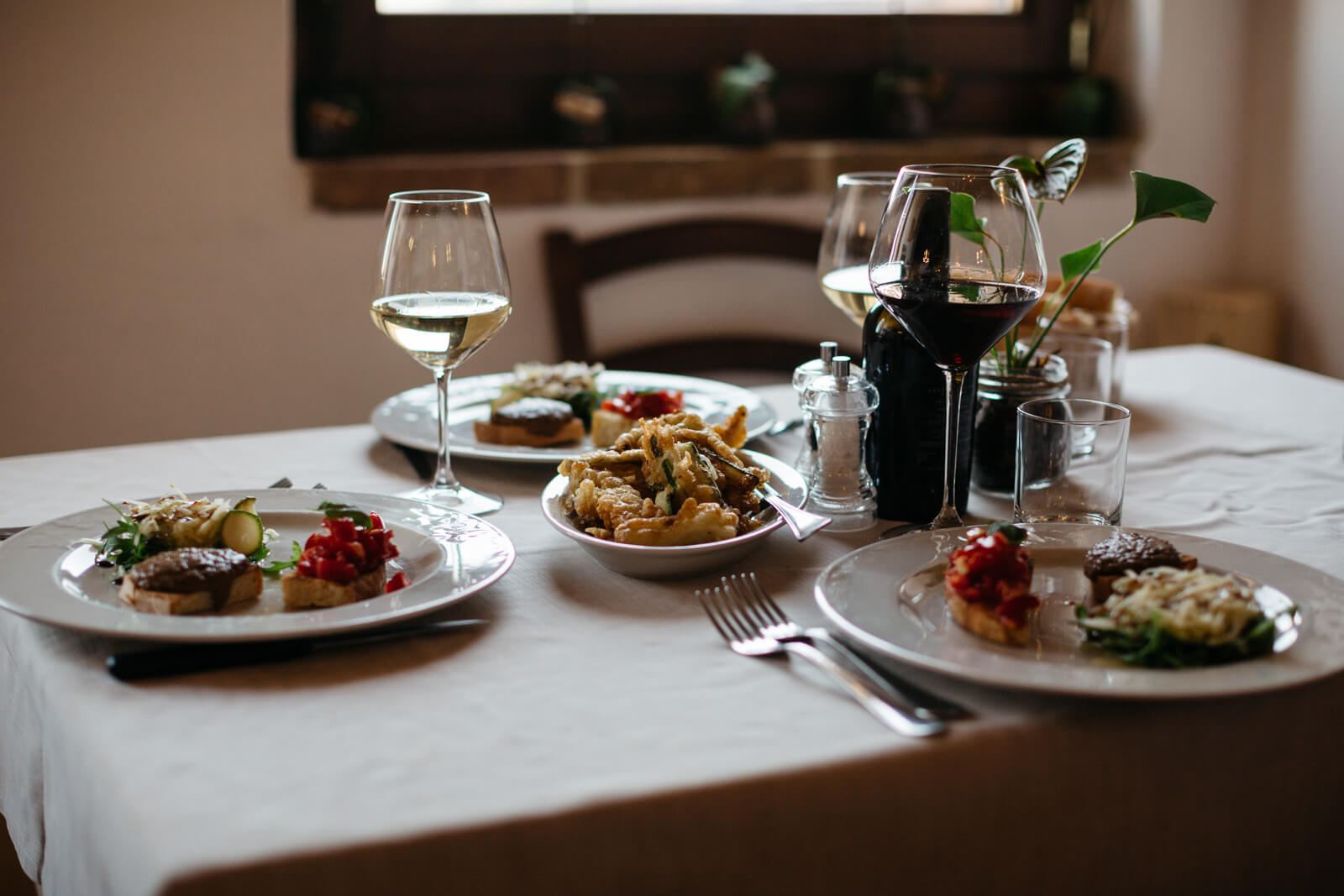 spread of food on a table for three with glasses of wine