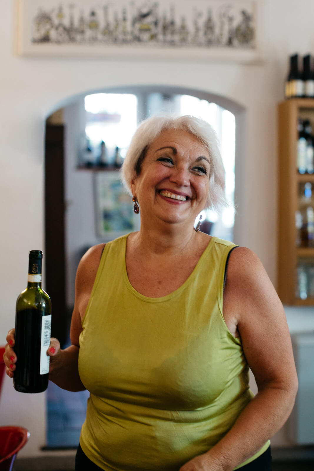 Woman smiling while holding bottle of red wine